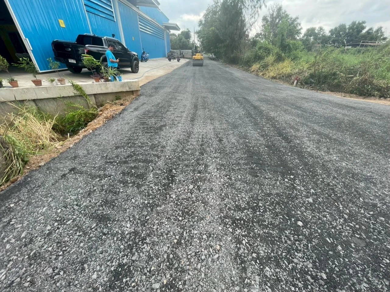 ภาพรวมถนนหินคลุกและรถบดขณะเก็บผิวทาง